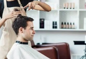 Aura stylist trimming a client's hair with scissors in a bright, modern salon chair